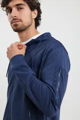 Cardigan de tejido de punto color azul piedra melange, con cuello redondo, cierre frontal completo y bolsillos laterales.