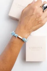 Pulsera de piedras naturales celestes y perla de agua dulce, con cierre de acero quirúrgico con baño de oro y dije de corazón dorado. Largo de 17cm y 4 cm de extensión.