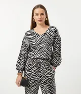 Blusa de viscosa con estampado animal print en blanco y negro, escote en V, mangas largas abullonadas con puños ajustados y dobladillo mullet.