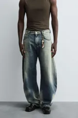 Pantalón de jean celeste con efecto lavado, corte holgado desde la cadera que se estrecha ligeramente en el bajo, tiro medio, cinco bolsillos y cierre frontal con cremallera y botón.