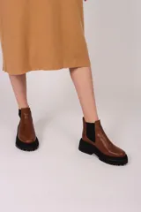 Borcegos negros de cuero vacuno con elástico lateral, suela track y tirador trasero.