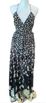 Maxi vestido negro con estampado de margaritas blancas, espalda descubierta y detalle de borla negra colgante.