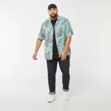 Camisa celeste con estampado de hojas de palmera en tonos negro y blanco, de corte holgado y manga corta.