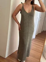 Vestido largo tejido con hilo de algodón y lurex color verde oliva. Silueta trapecio, escote en V, tiras regulables con borlas, espalda abierta y tajos laterales.