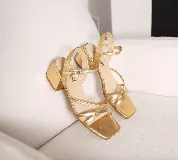 Sandalias doradas de cuero metalizado con tiras finas cruzadas, plantilla cuadrada y taco bajo de 4 cm.