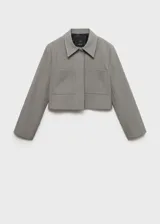 Chaqueta corta gris con cuello camisero, cierre frontal con botones ocultos, dos bolsillos de parche delanteros y forro interior.