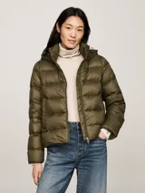 Campera puffer verde militar de Tommy Hilfiger, con capucha ajustable, cierre frontal con cremallera, dos bolsillos delanteros con botón a presión y parche con el logo de la marca en la manga.