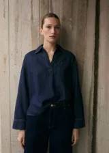 Camisa de jean azul oscuro, de corte holgado, manga larga y cuello clásico con abertura en V.