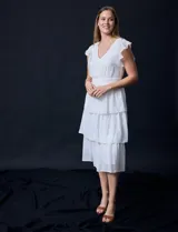 Vestido blanco de gasa con capas de la marca Julia Jordan. Tiene escote en V, mangas cortas con volados, corte en la cintura, abertura central en la espalda con cierre invisible y forro interno a tono.