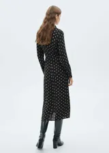Vestido midi camisero negro con estampado de lunares color beige, cierre frontal con botones, lazo en la cintura y mangas largas con puños abotonados.