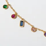 Gargantilla dorada con cadena fina y dijes colgantes de diferentes formas y colores.