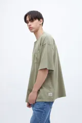 Remera color gris claro, de algodón lavado con textura extra suave, calce boxy y bolsillo en el pecho.