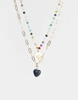 Collar corto dorado con cadena de eslabones y cadena de cuentas de colores. Incluye dije de moneda dorada con estrella grabada y dije de corazón de piedra azul.