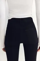 Jeans skinny de tiro alto en denim azul oscuro, con cinco bolsillos y cierre frontal con cremallera y botón metálico.
