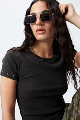 Remera blanca de punto acanalado con cuello redondo y mangas cortas. Presenta apliques de strass en el escote y las mangas.