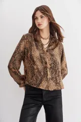 Camisa fluida con estampado reptil, escote redondo con apertura frontal y mangas largas terminadas en puño con botón.