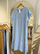 Vestido midi azul marino de lino, corte recto, con cuello en V, mangas cortas y detalle de flecos en ruedo y mangas.