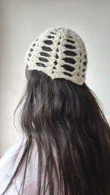Gorro tipo turbante de tejido crochet color crudo, con diseño calado y lentejuelas plateadas.