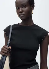Camiseta negra de tejido de canalé con cuello redondo y sisas con ojales metálicos.