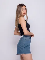 Short de jean azul con terminaciones desflecadas, cinco bolsillos, botón y cierre metálico.