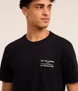 Remera negra de algodón, corte comfort, mangas cortas y cuello redondo. Estampa frontal con lettering "On the Brink of Adventure" y estampa trasera con esqueleto en canoa.