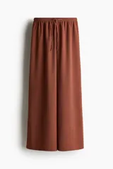 Pantalón marrón de punto texturado, corte holgado, tiro alto, piernas rectas, elástico en la cintura y cordón para ajustar.
