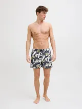 Short de baño con estampado floral en tonos blanco, verde y marrón sobre fondo azul oscuro. Cuenta con cintura elástica, cordón ajustable, bolsillos laterales y trasero.