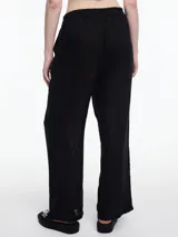 Pantalón negro de lino con elástico en la cintura y calce relajado. Incluye bolsillos laterales y un bolsillo invertido. Detalles de bordado tipo pespunte en color gris recorren la pierna y el bajo.