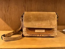 Cartera bandolera de cuero con estampado de piel de serpiente en tonos marrón y beige. Tiene correa larga ajustable y cierre con solapa.