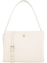 Cartera satchel color crema con acabado granulado, cierre de cremallera, asa superior y correa extraíble ajustable. Insignia del monograma TH dorada en la parte delantera.