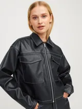 Campera corta de cuero sintético negra con cuello clásico, cierre frontal con cremallera, bolsillos con solapa en el pecho y costuras blancas en contraste.