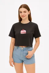 Remera cropped negra de algodón con estampado de un trozo de torta con cereza.