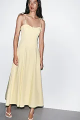 Vestido midi amarillo claro, con escote corazón con volantes y tirantes finos ajustables con lazo. Falda acampanada con forro interior.