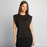 Camiseta negra sin mangas con hombreras marcadas y cuello redondo. Corte recto y holgado.