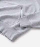 Buzo tipo canguro de color gris melange, con capucha, bolsillo canguro frontal y puños y bajo acanalados. Corte recto.