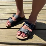 Sandalias de cuero sintético color verde militar, con plantilla marrón y hebillas metálicas doradas.