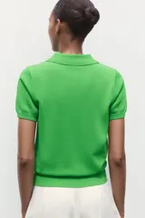 Top azul eléctrico de punto, con cuello polo, manga corta y cierre frontal con botones negros.