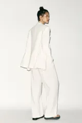 Blazer blanco de corte oversize, con cuello solapa, manga larga con hombreras, bolsillos de doble vivo en el delantero, aberturas en la espalda y cierre cruzado con botones.