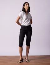 Pantalón capri blanco de algodón elastizado. Pretina con pasadores, botón y cierre. Delantera con bolsillos. Trasera con bolsillos simulados.