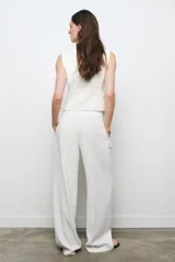 Pantalón de tiro alto color blanco, de corte recto y pierna ancha, con bolsillos laterales y pinzas frontales.