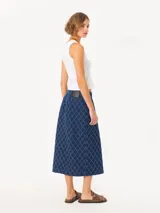 Pollera midi de denim azul con diseño de rombos desflecados, corte recto, tiro alto, abertura frontal con botones metálicos y botón interno de seguridad.