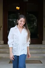 Camisa blanca de manga larga con cuello camisero y cierre frontal con botones. Detalle de bordados perforados combinados a tono.