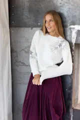 Buzo color blanco con apliques de estrellas, de corte holgado y tejido suave.