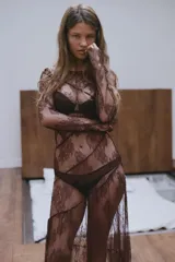 Vestido midi semitransparente de encaje floral color borgoña, con cuello barco, mangas largas y espalda con escote en V. Presenta costuras marcadas y terminaciones onduladas.