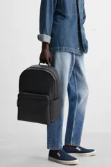 Mochila negra con textura grabada, compartimento principal con cierre de cremallera, compartimento acolchado interior para dispositivos electrónicos de hasta 13 pulgadas, bolsillo frontal con cierre de cremallera, dos bolsillos laterales planos, asa de mano y dos asas de hombro ajustables.