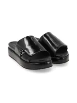 Sandalia de cuero charol negro con plataforma y tira ancha sobre el empeine con aplique metálico circular.