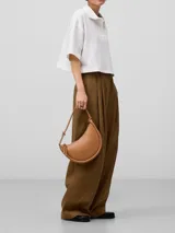 Bolso de hombro color marrón claro, con textura napa, un compartimento, cierre de cremallera, bolsillo interior con cierre de cremallera, asa tubular con pieza metálica y logo grabado.