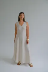 Vestido largo color beige confeccionado en lino italiano, de corte recto, sin mangas y escote en V. Presenta ruedo desflecado.