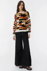 Sweater tejido a mano con diseño geométrico en tonos marrón, beige, negro y blanco.