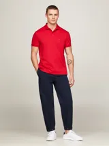 Chomba Tommy Hilfiger Essential de corte regular, color rojo, confeccionada en algodón. Presenta cuello tipo polo, cartera de dos botones y logo bordado en el pecho.